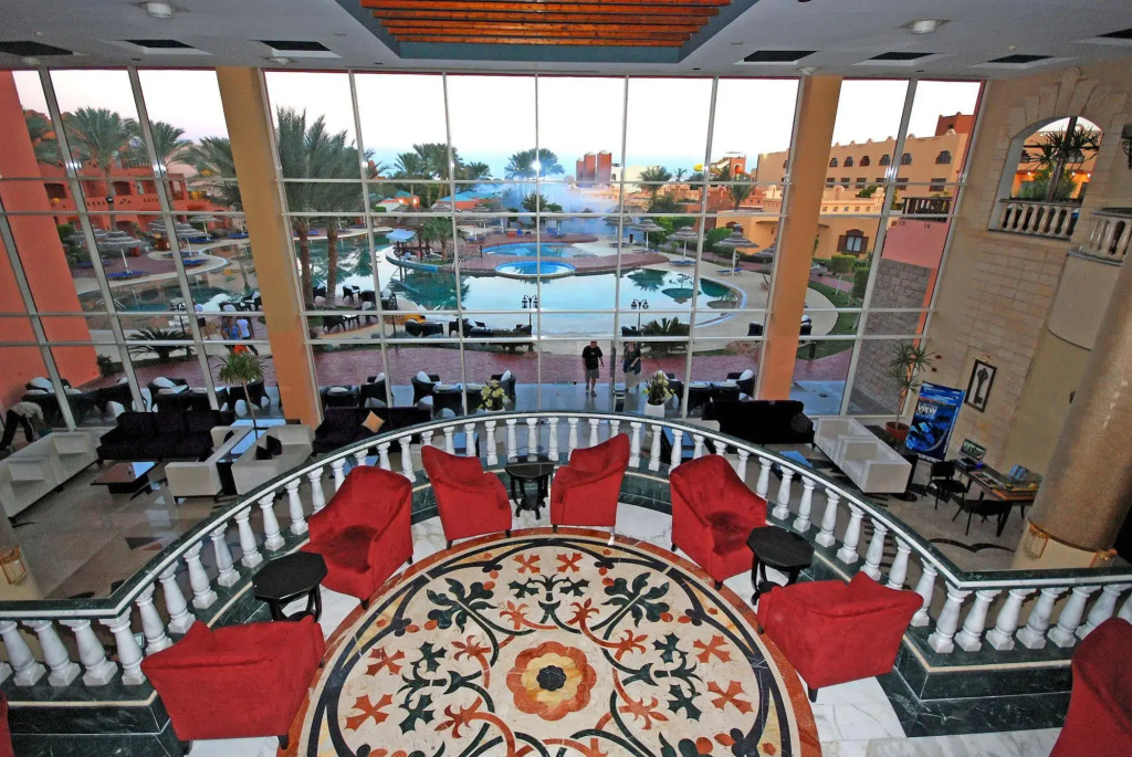 Nubian Island, Families and Couples only: A bright hotel lounge with red armchairs overlooks a landscaped outdoor pool courtyard.