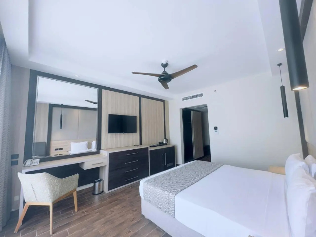 Panorama Naama Heights Sharm El Sheikh: Bright bedroom with a white bed, wall-mounted TV, and a built-in desk with chair.