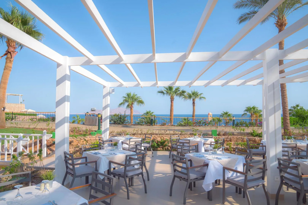 Savoy Sharm El Sheikh hotel: Dine outdoors beneath a shaded pergola with views of the sea and palm trees.