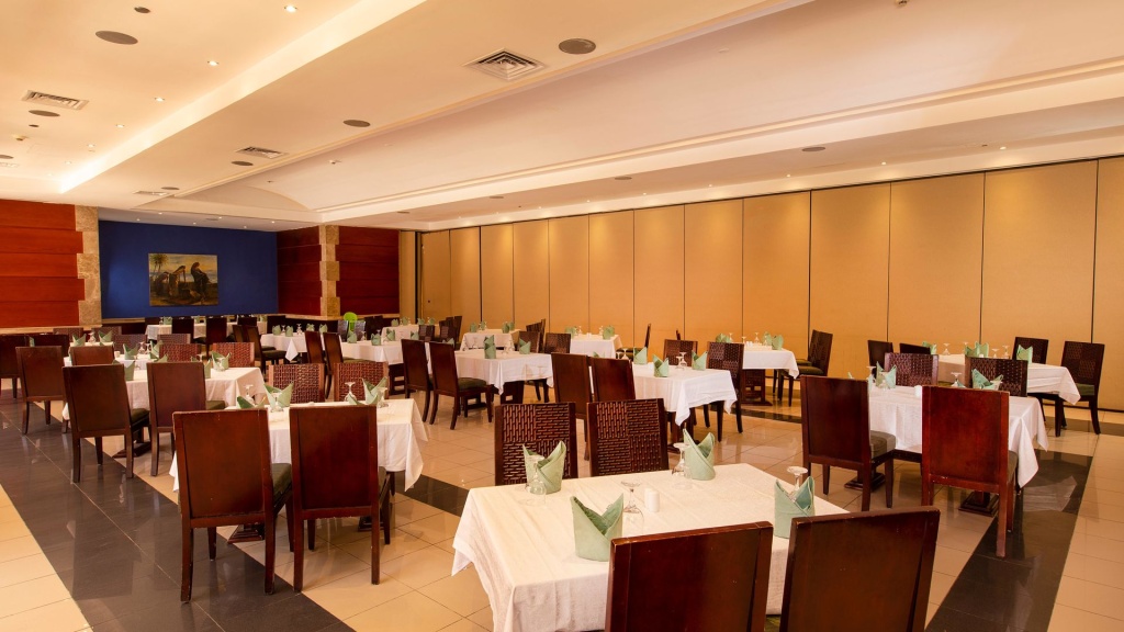 Naama Bay Hotel & Resort: Spacious dining room with neatly set tables and dark wood chairs.