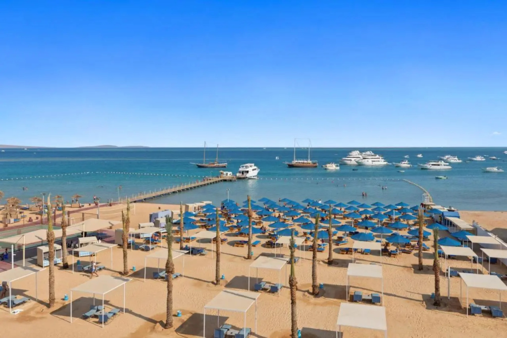 Pickalbatros Blu Spa Resort - Adults Friendly 16 Years Plus: Relax on a palm-lined sandy beach with shaded loungers and views of boats across the sea.