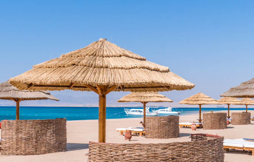 The Cascades Golf Resort Spa and Thalasso: Thatched parasols and loungers line a sunny sandy beach beside clear blue water.