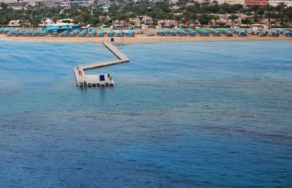 Pharaoh Azur Resort: A resort beach lined with loungers and turquoise umbrellas, with a pier stretching out over the sea.
