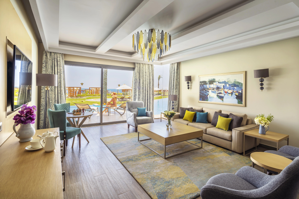 Rixos Premium Magawish Suites and Villas: Bright suite living room with a furnished terrace, pool, and sun loungers just beyond the glass doors.