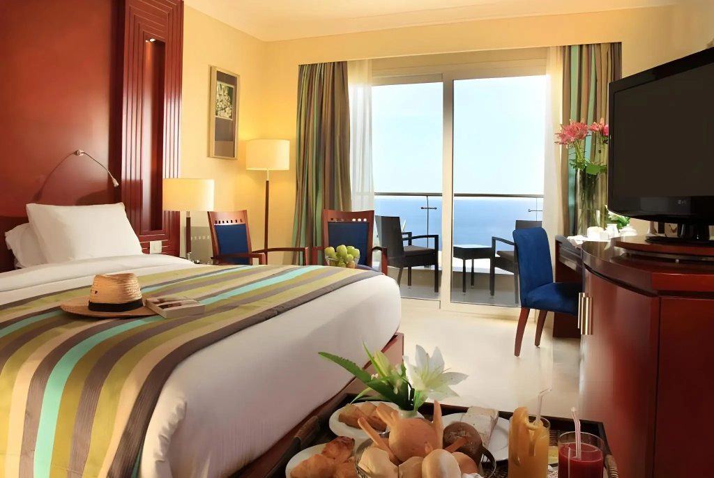 Xperience Sea Breeze Resort: Bright guest room with a private balcony overlooking the sea, a large bed, and a flat-screen TV.