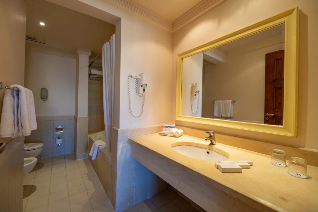 Continental Plaza Beach Resort (Ex. Inter Plaza Beach): Bathroom with a long stone vanity, large mirror, bathtub with shower curtain, and toilet.