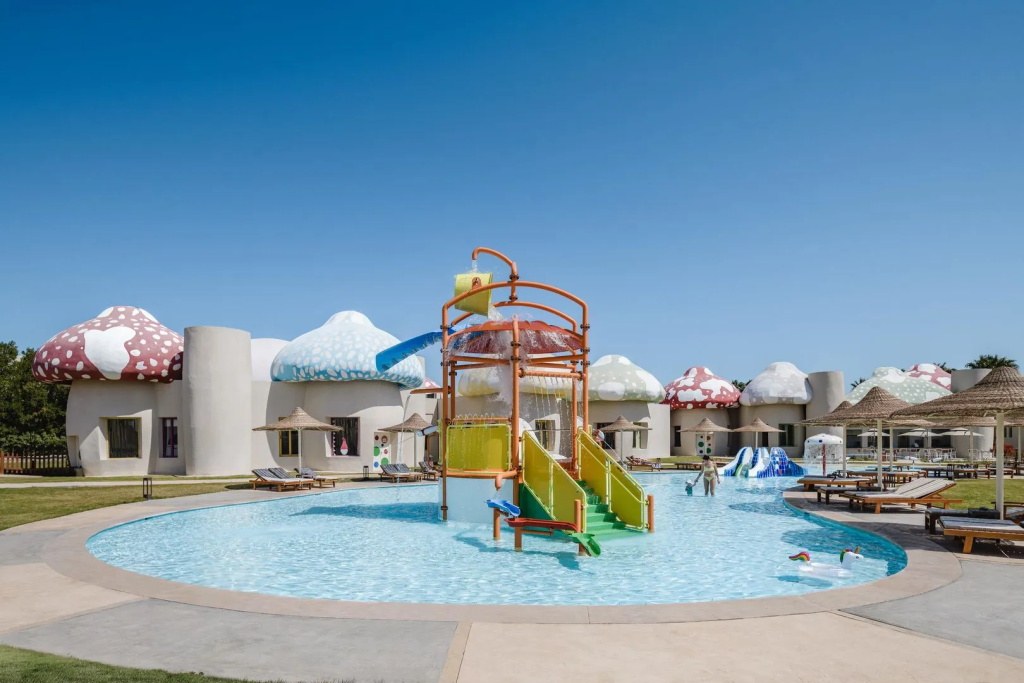 Xanadu Makadi Bay - High Class All Inclusive: A family-friendly pool features a colorful water-play structure, with sun loungers and shaded seating nearby.