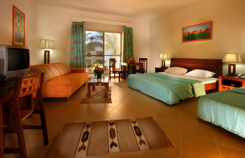 Xperience St. George Homestay: A spacious guest room with two beds, a sofa, a television, and a balcony overlooking palm trees.