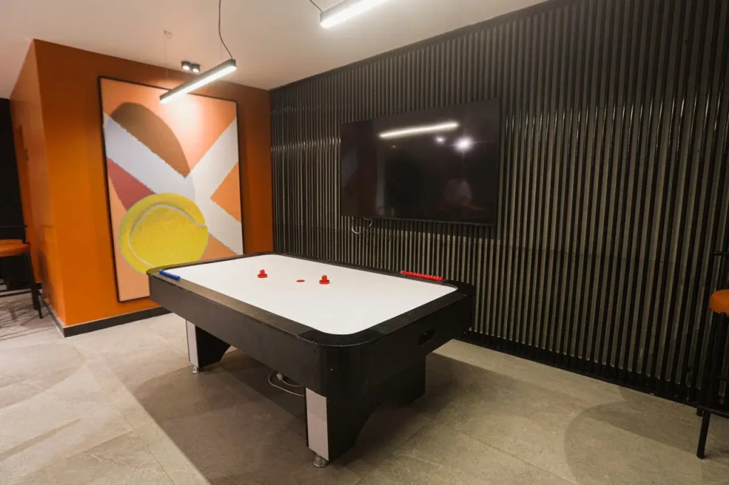 Flow Spectrum Resort Sahl Hasheesh: Play air hockey in a colorful indoor game area with a wall-mounted TV.