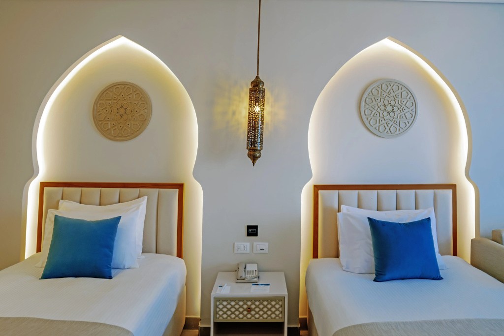 Sunrise Remal Beach Resort: A bright twin bedroom with two separate beds, blue accent pillows, and a shared bedside table.