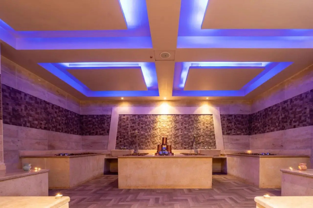 El Karma Aqua Beach Resort: A tiled indoor wellness-style space with a central stone platform, perimeter counters, and blue accent lighting.