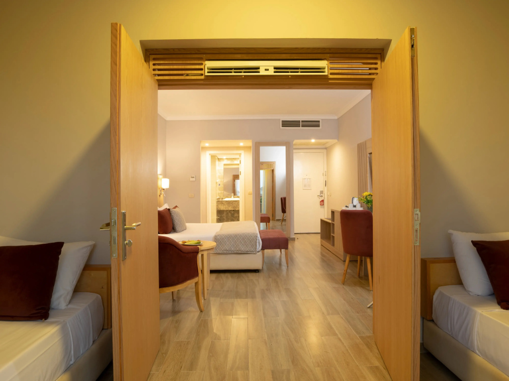 Stella Beach Resort & Spa, Makadi Bay Resort: A warm, wood-floored guest suite with twin beds and a separate sitting area.