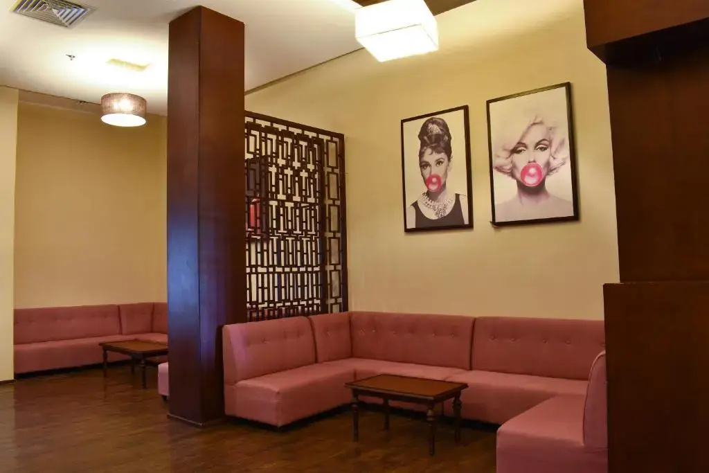 Parrotel Lagoon Waterpark Resort: An indoor lounge with pink upholstered banquette seating, low tables, and framed wall art.