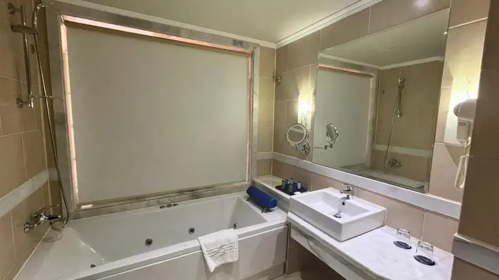 Parrotel Lagoon Waterpark Resort: A spacious bathroom with a large jetted soaking tub, a separate vanity sink, and a wide mirror.