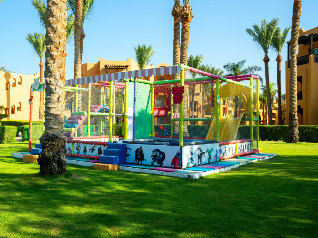Stella Beach Resort & Spa, Makadi Bay Resort: Colorful enclosed children’s playground set on a palm-lined resort lawn.