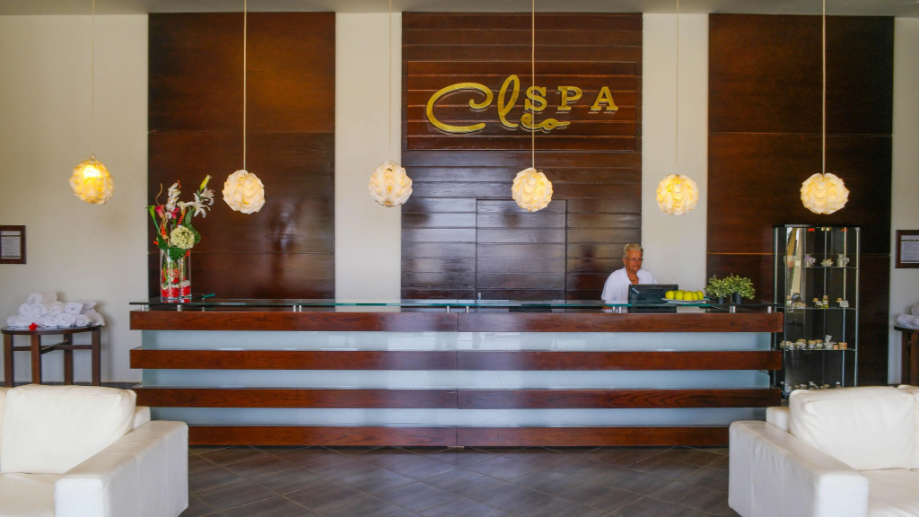 Cleopatra Luxury Resort Makadi Bay: A spa reception desk with warm wood finishes, soft pendant lighting, and nearby seating.