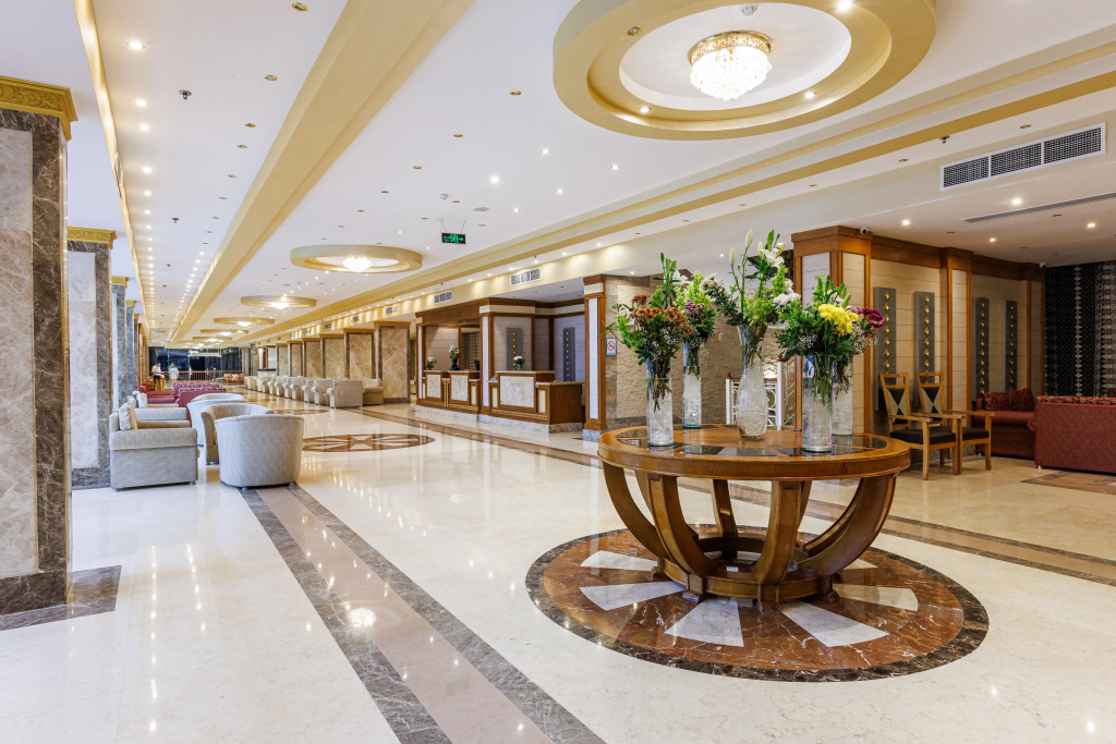 Solara Aqua Park Resort by SUNRISE: A bright, spacious lobby features a reception desk, lounge seating, and a flower-adorned centerpiece table.
