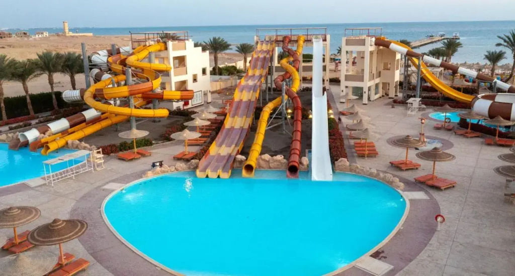 El Karma Aqua Beach Resort: A large outdoor pool and water slides are surrounded by sun loungers and shaded seating.