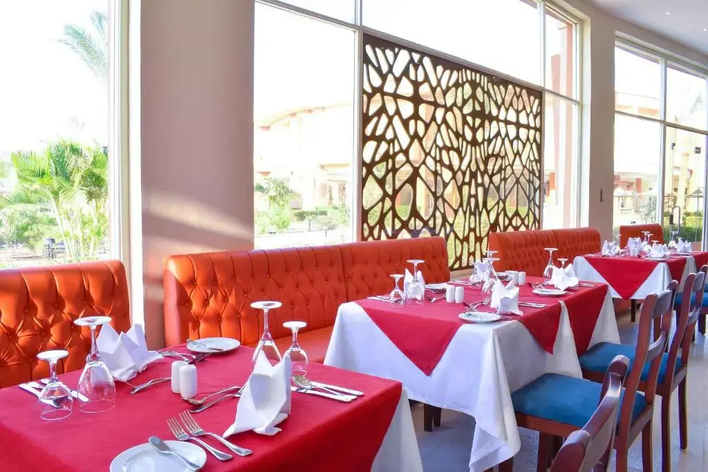 Parrotel Lagoon Waterpark Resort: Bright dining room with red booth seating and tables set for meals.