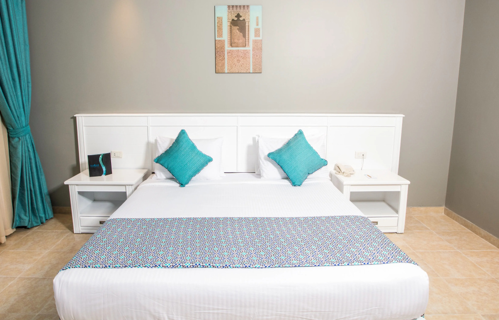 SUNRISE Garden Beach Resort: A bright guest bedroom with a large bed, turquoise accent cushions, and bedside tables.