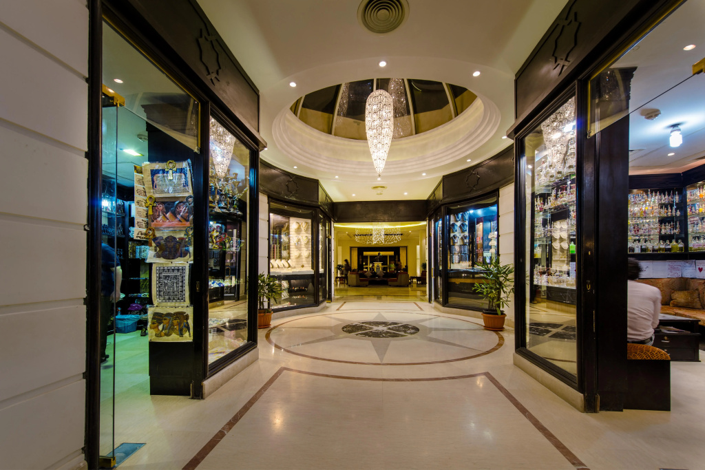 Concorde El Salam Sharm El Sheikh: A polished indoor shopping arcade with glass-fronted displays, decorative chandeliers, and a lounge area visible beyond.