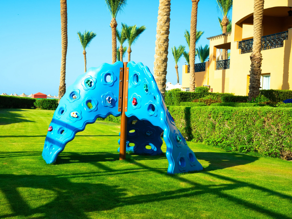 Stella Beach Resort & Spa, Makadi Bay Resort: A colorful climbing structure sits on a sunny, palm-lined lawn.