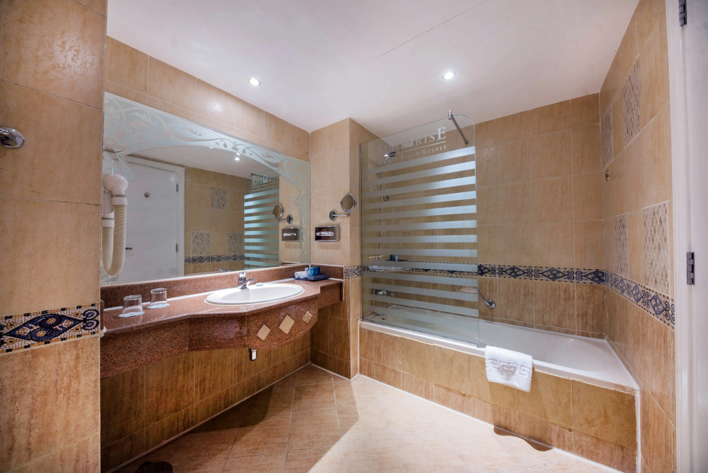 SUNRISE Garden Beach Resort: A spacious tiled bathroom with a vanity, bathtub, and glass shower screen.