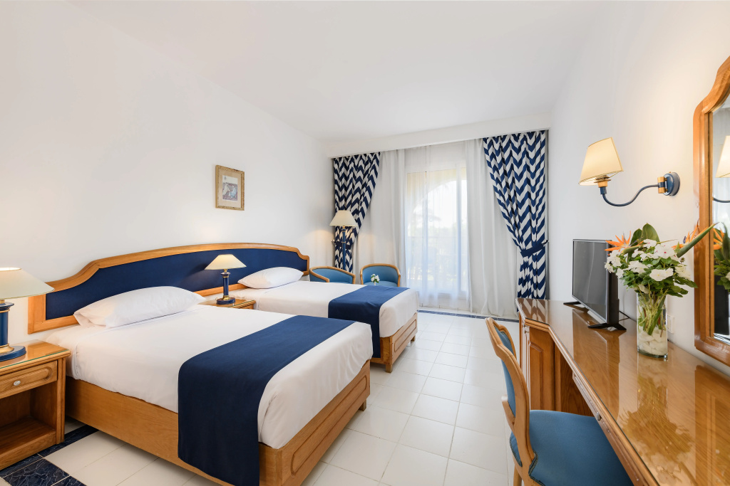 Desert Rose Resort: Bright twin room with two beds, a desk and a television.