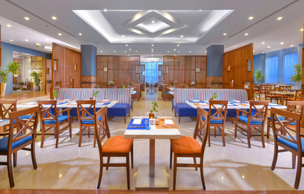 JAZ Soma Beach: A spacious indoor restaurant dining room with booth seating, wooden chairs, and set tables.