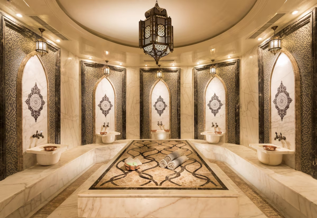 Rixos Premium Seagate: An ornate marble hammam features a raised central platform, washing basins, and warm lantern lighting.