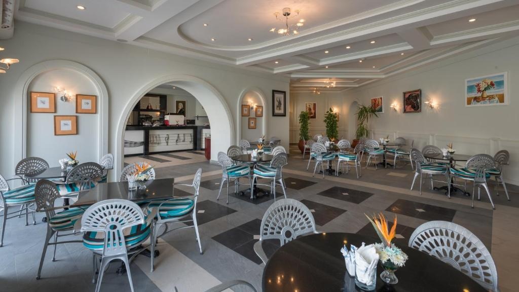 Pickalbatros Citadel Resort: A spacious indoor restaurant with arranged dining tables, turquoise-accented chairs, and a service counter.