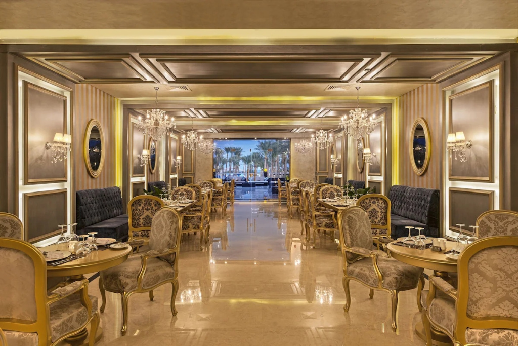 Rixos Premium Seagate: An elegant restaurant dining room with set tables, upholstered seating and crystal chandeliers.