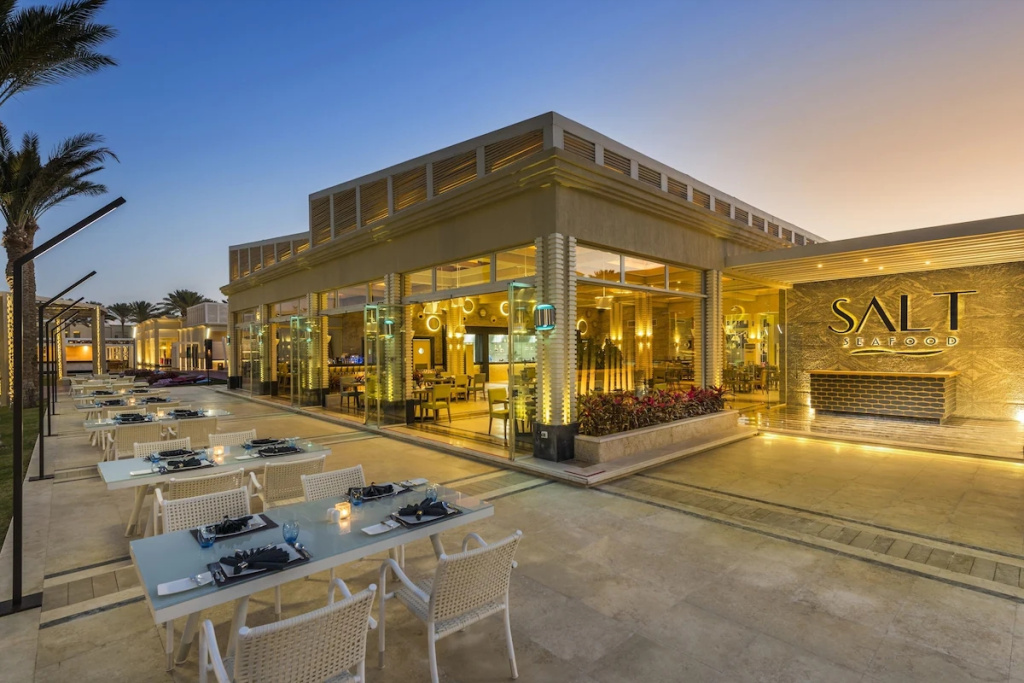 Rixos Premium Seagate: SALT Seafood offers glass-fronted indoor seating and a spacious outdoor dining terrace with set tables.